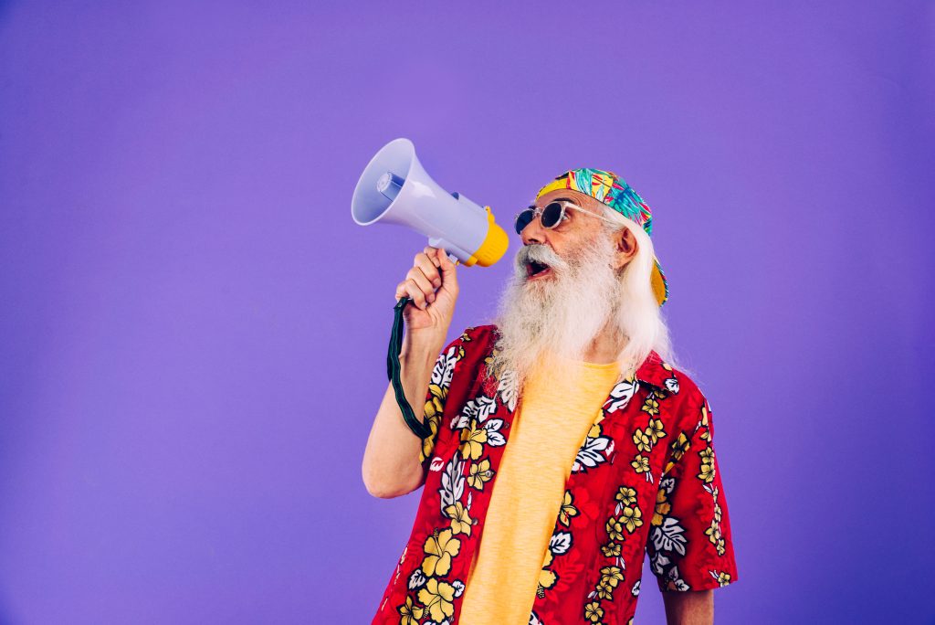 Old man in hippie look speaks through a megaphone.  