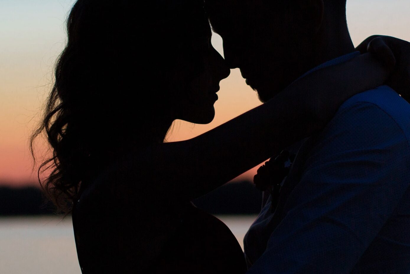 Mann und Frau umarmen sich am Strand, im Sonnenuntergang